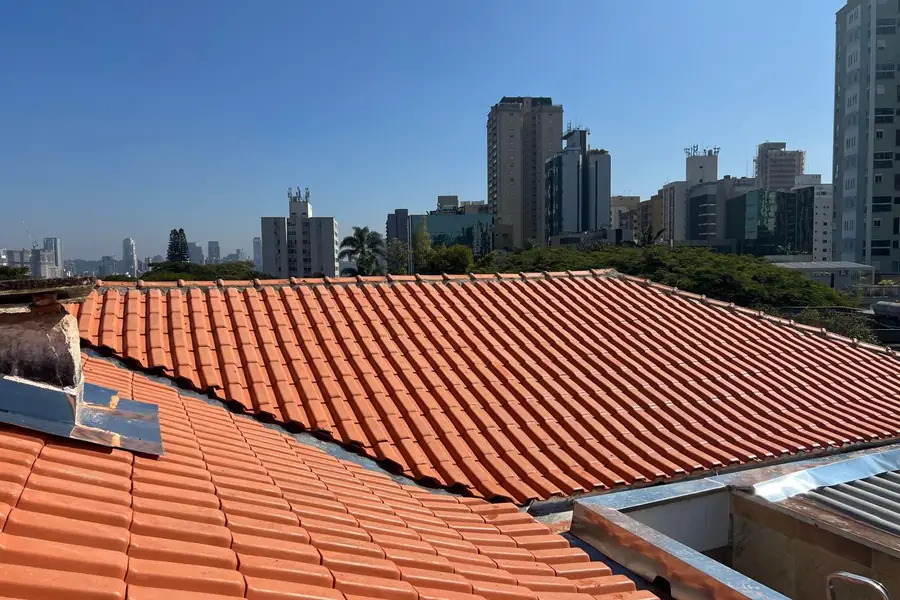Telhado de telhas cerâmicas novo, com prédios de São Paulo ao fundo