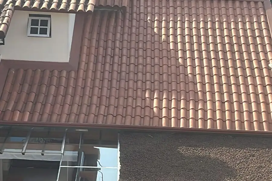 Cobertura cerâmica de casarão durante a recuperação, com parte das telhas já tratadas