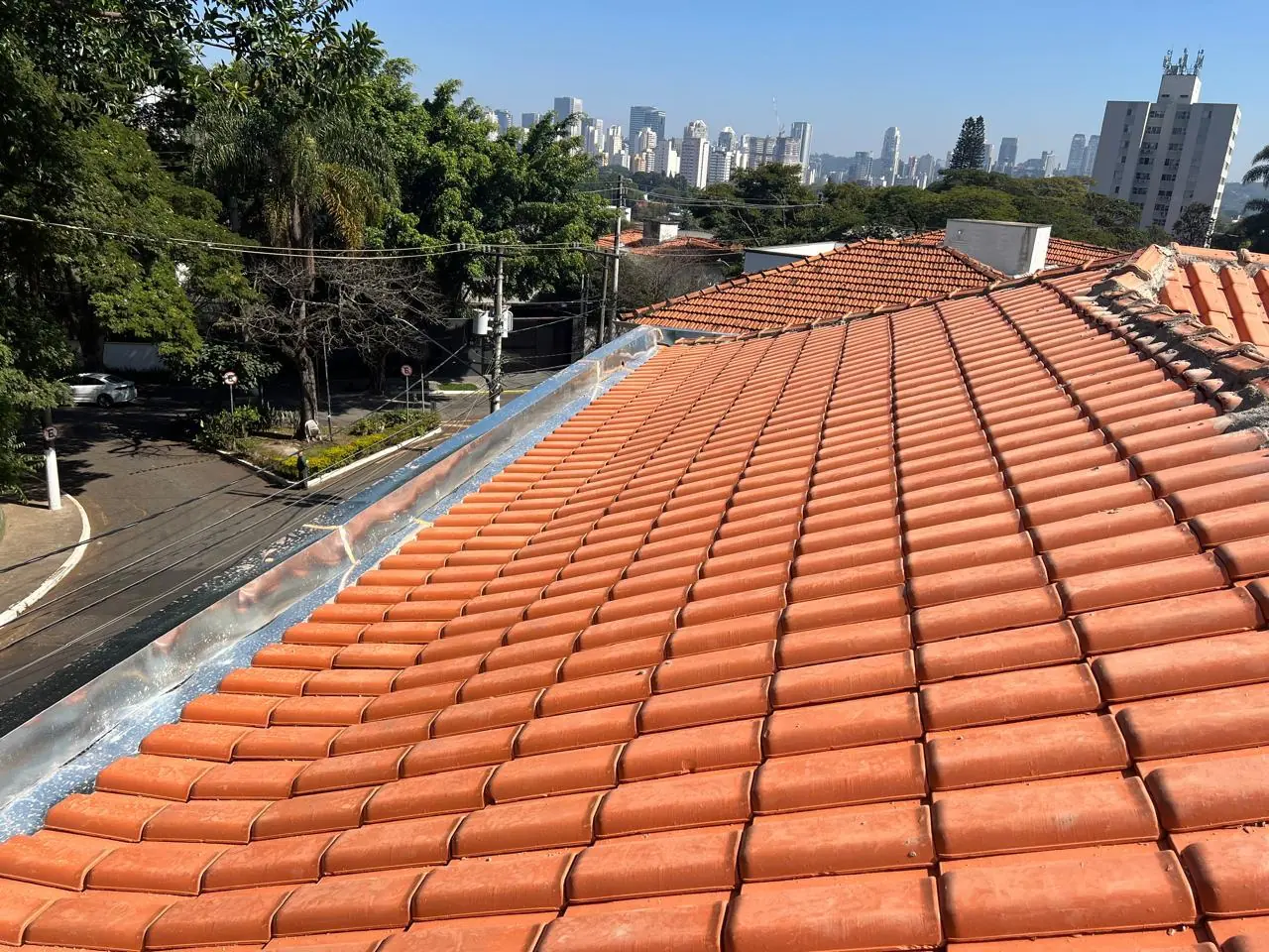 Telhado de telhas cerâmicas executado pela Ideal Telhados, com a cidade de São Paulo ao fundo
